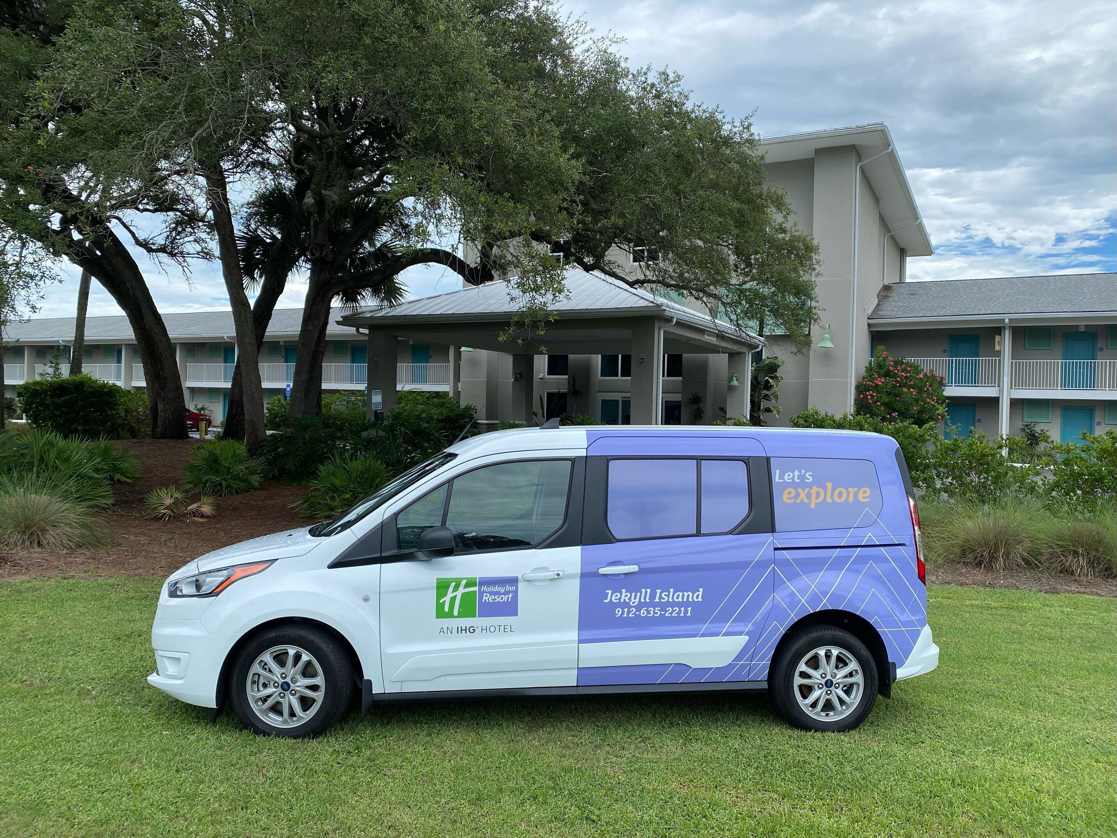 A white van parked in front of a building with a sign reading "Holiday Inn Resort Jekyll Island 912-635-2211."