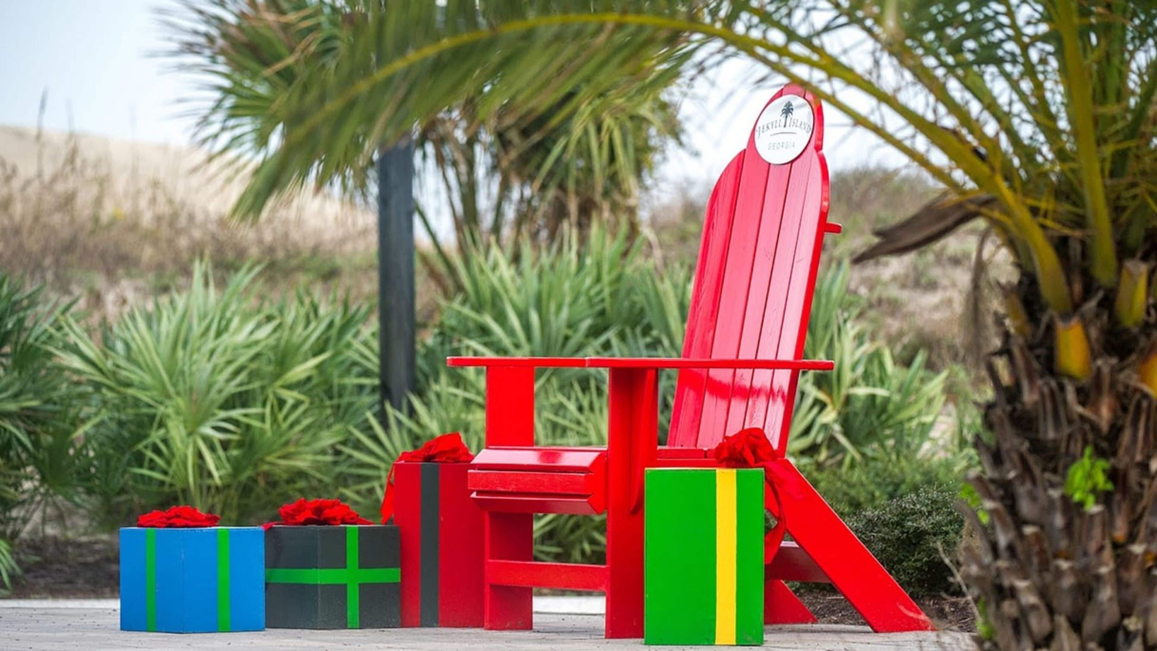 A red Adirondack chair with a white label, surrounded by colorful gift boxes.