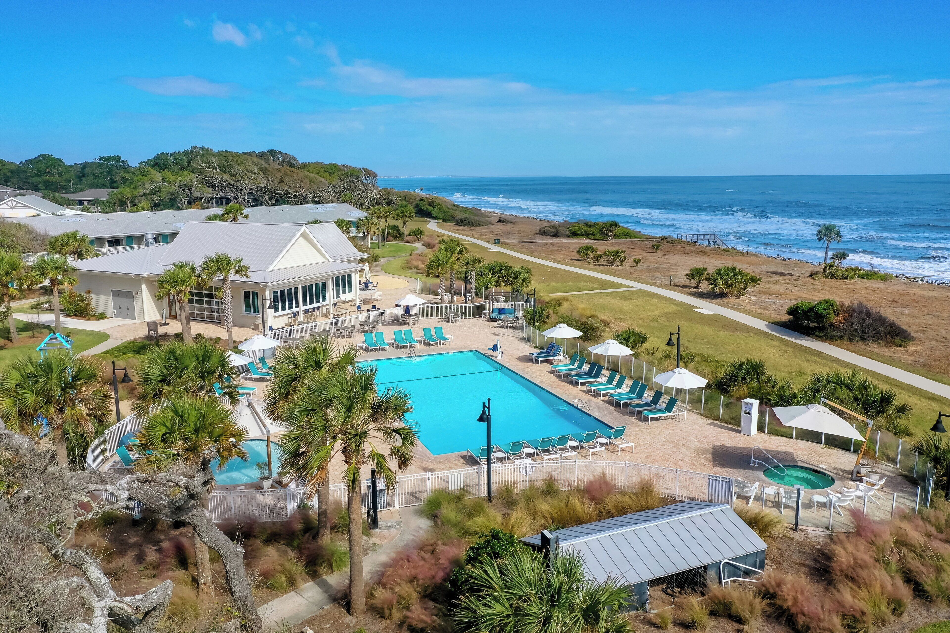 A resort with a large pool, sun loungers, and a view of the ocean.