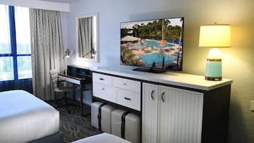 A hotel room with a bed, a desk with a chair, a television, and a lamp.