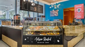 A coffee shop interior with a menu board, a pastry display, and a sign indicating seasonal beverages. - Wyndham Lake Buena Vista – Disney Springs® Area (Lake Buena Vista)
