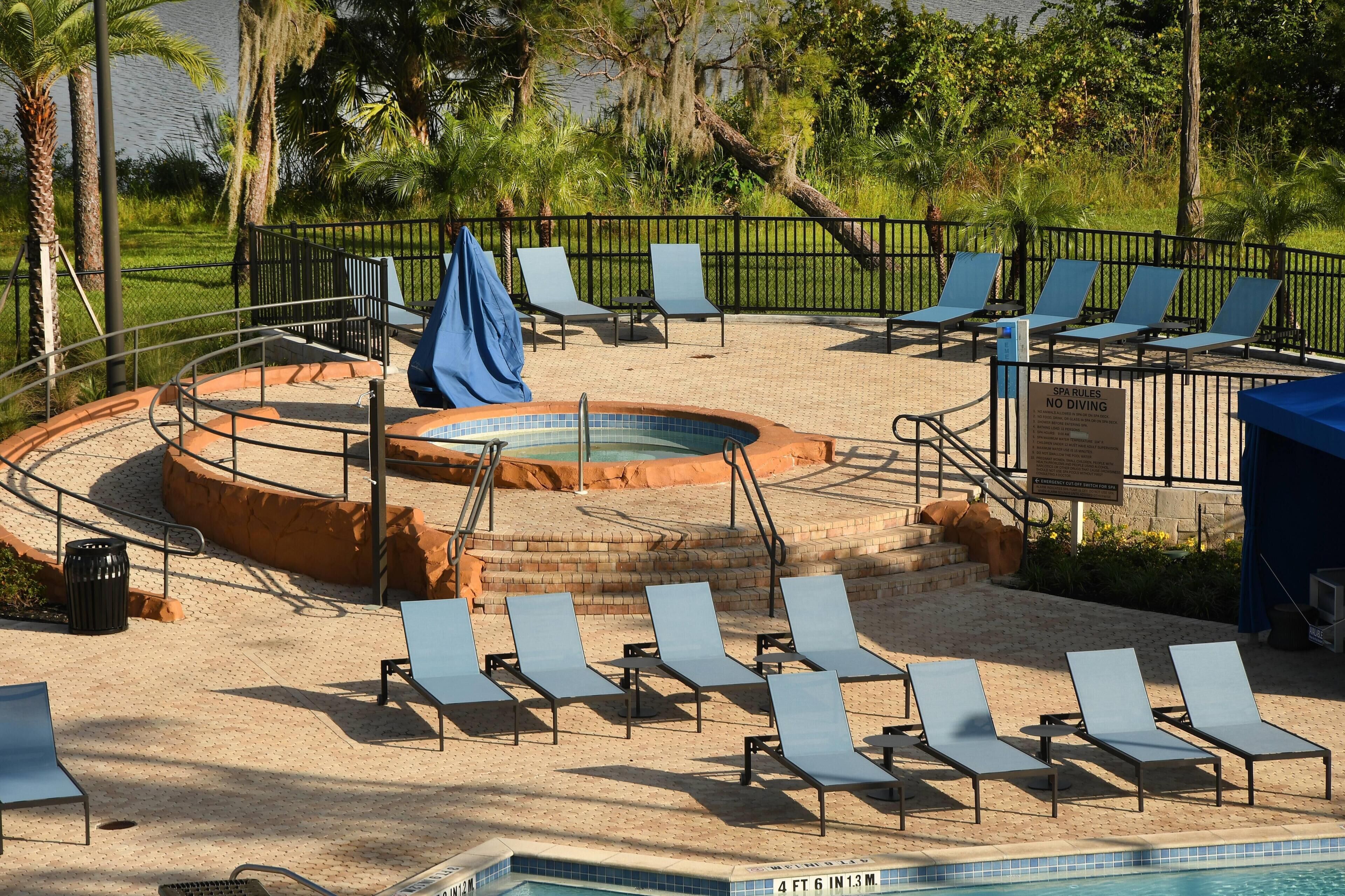 A pool area with lounge chairs, a hot tub, and a sign indicating no diving.