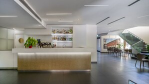 Een moderne hotel lobby met een receptiebalie, een bar, zitplaatsen en een trap.
