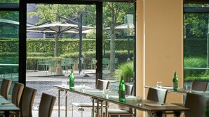 Een terras met tafels en stoelen, een grindpad en parasols.