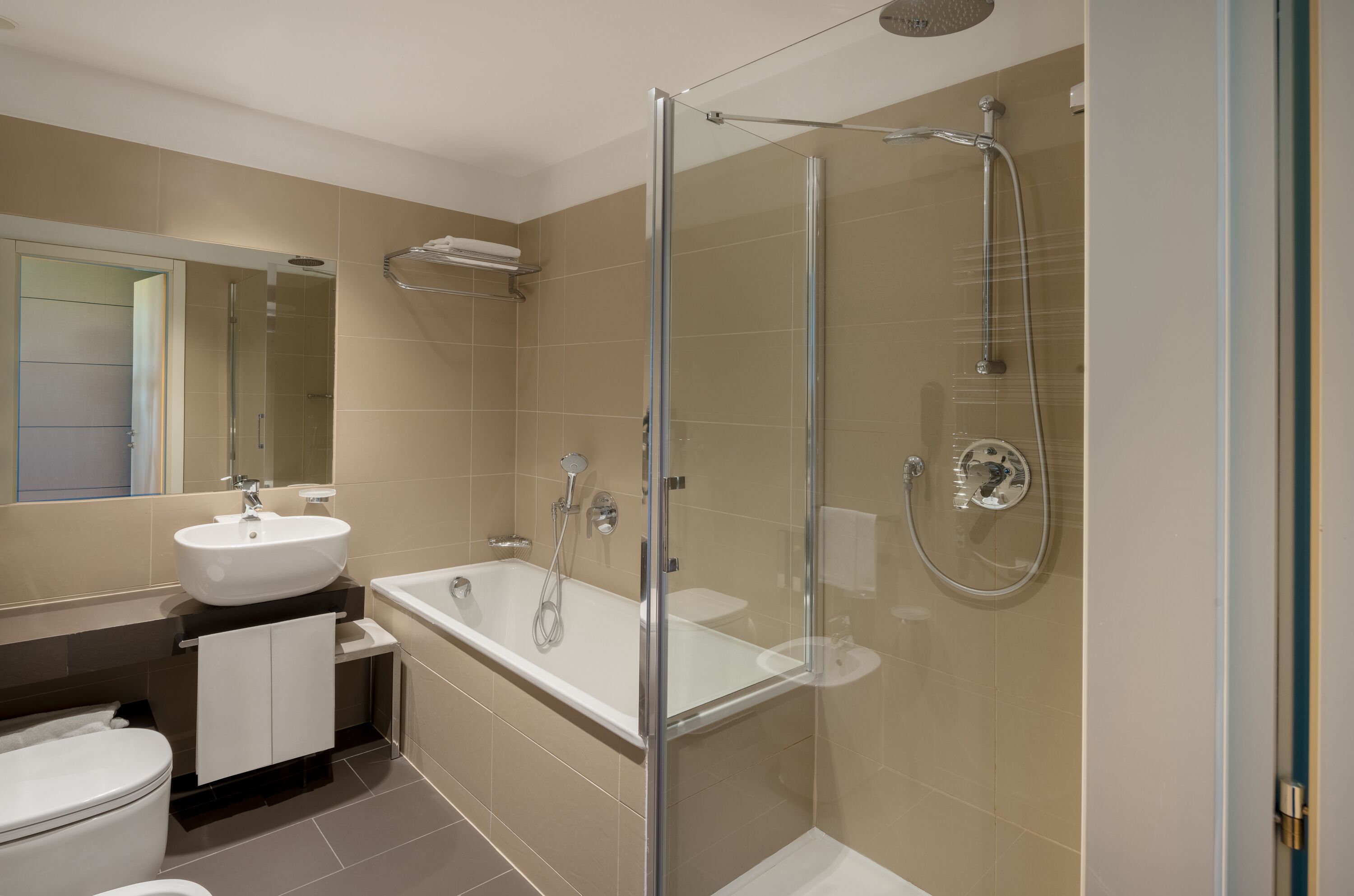 A modern bathroom with a glass-enclosed shower, a white sink, and a toilet.