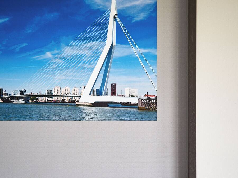 A framed photograph of a modern bridge with cables, a clear blue sky, and a city skyline in the background.
