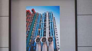 A framed photograph of a tall industrial structure with multiple pipes and a crane, mounted on a textured wall.