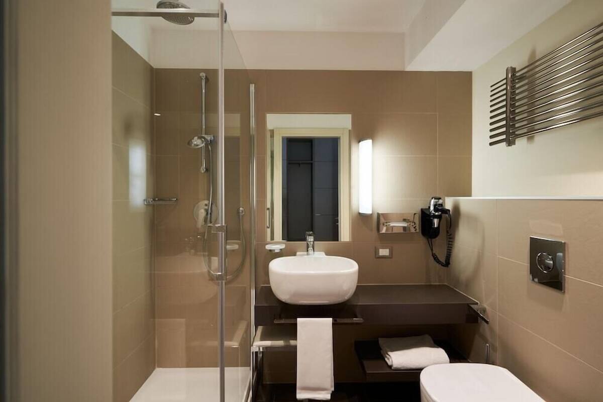 Une salle de bain moderne avec une douche à parois de verre, un lavabo, des toilettes et un porte-serviettes.