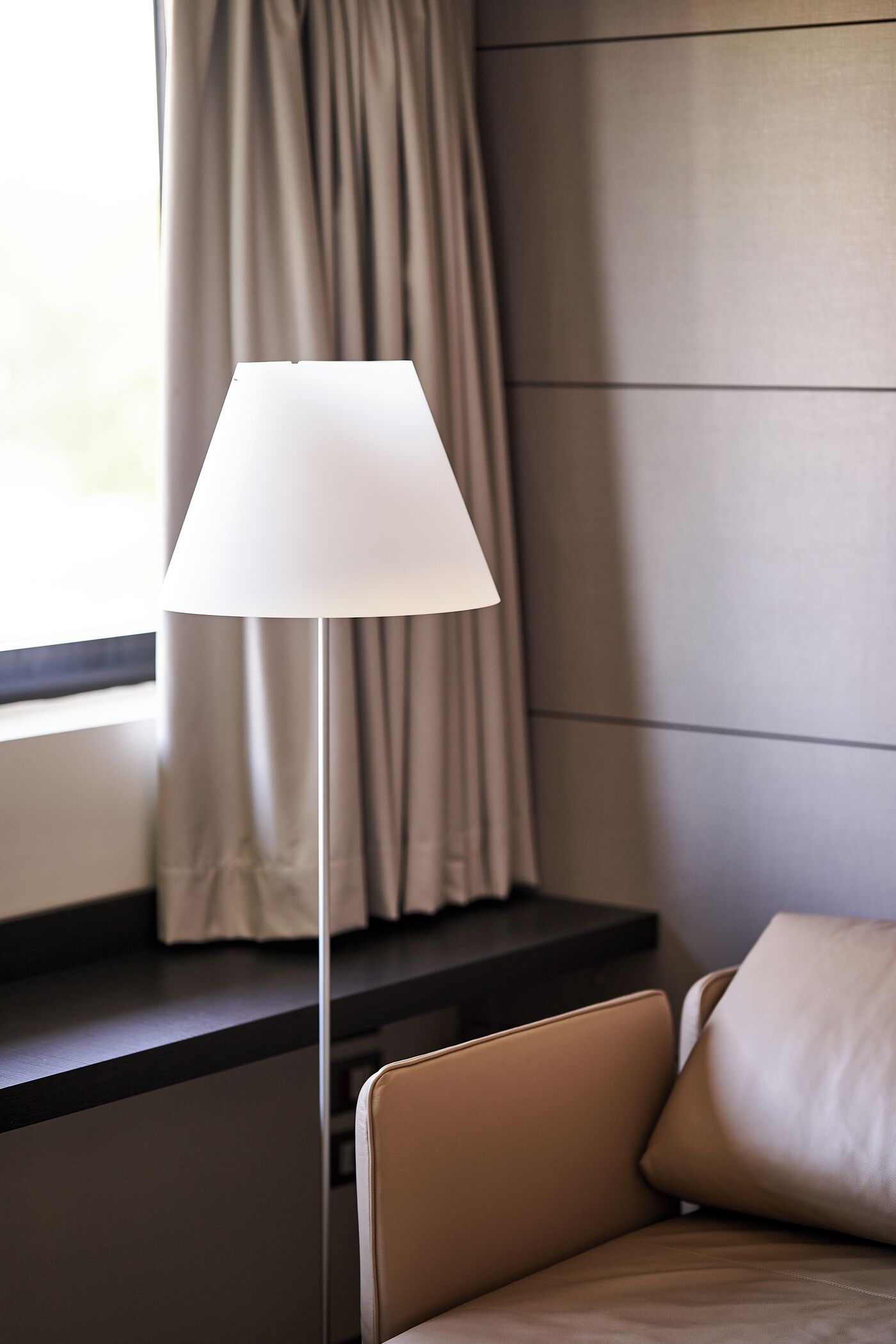 A modern room with a floor lamp, a sofa, and a window with curtains.