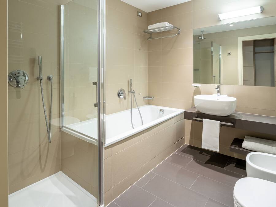 Un baño moderno con ducha envuelta en vidrio, una bañera independiente y un tocador con lavamanos y espejo.