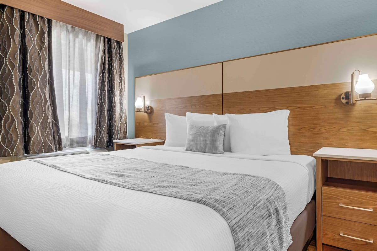 A hotel room with a large bed, wooden headboard, two bedside tables, and a nightstand.