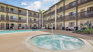 A multi-story hotel with a central courtyard featuring a hot tub and a swimming pool.