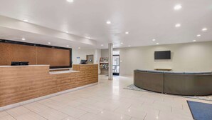 A modern reception area with a wooden reception desk, a curved seating area, and a flat-screen TV mounted on the wall.