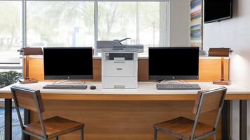 Un espacio de trabajo con dos monitores HP, una impresora y un teclado sobre un escritorio.