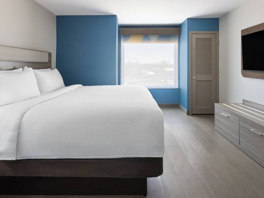 A modern hotel room with a large bed, a wardrobe, a television, and a window with a view.