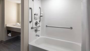 Une salle de bain moderne avec une baignoire blanche, des barres d’appui et une douchette à main.