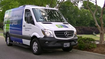 A white and blue delivery van with 'Holiday Inn Express' branding parked on a street.