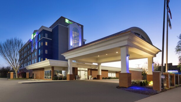 A hotel with a modern design, featuring a prominent entrance with a covered area and a flagpole with the American flag. - Holiday Inn Express Augusta Downtown by IHG (Augusta)