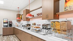 Une cuisine moderne avec des meubles en bois, un plan de travail blanc et divers produits alimentaires exposés.