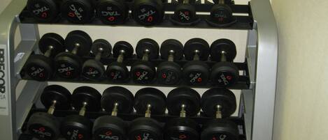 A wall-mounted dumbbell rack with multiple sets of dumbbells.