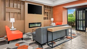 Un espace de vie moderne comprenant un canapé, deux fauteuils, une table basse, un téléviseur à écran plat et des étagères intégrées.