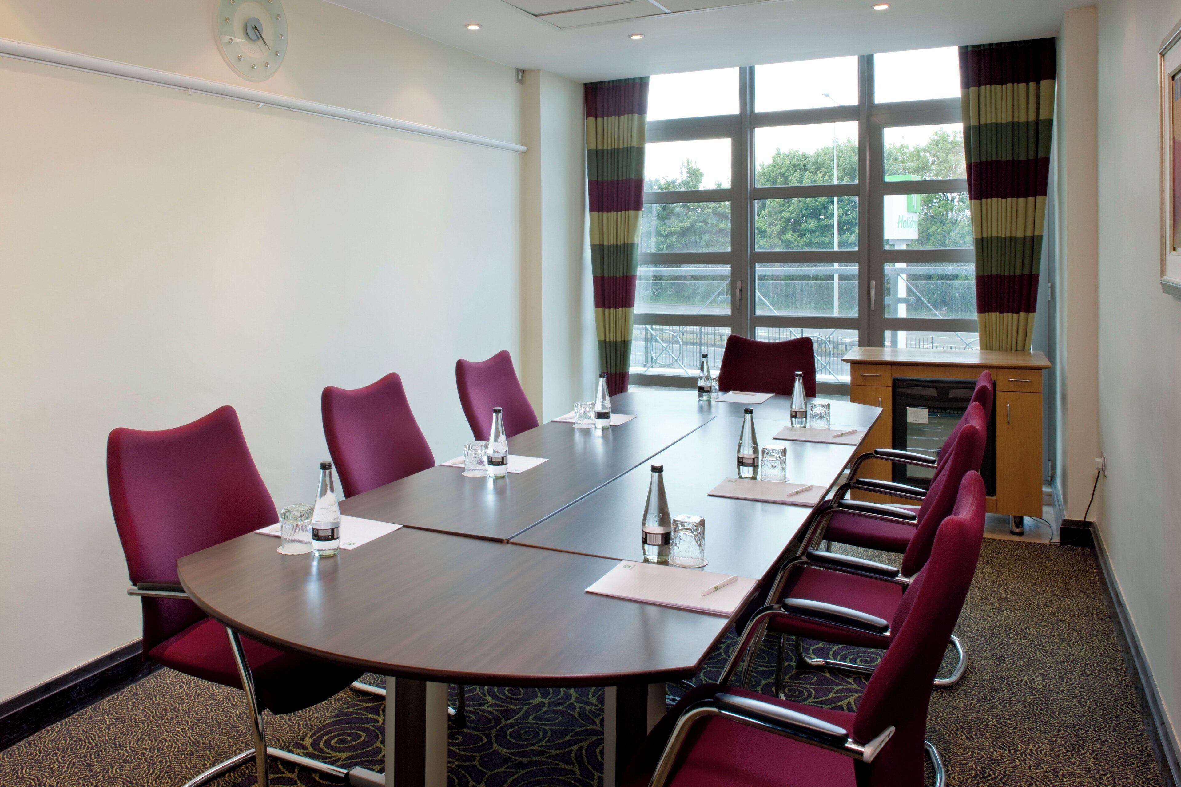 A conference room with a long table, chairs, water bottles, and a podium.