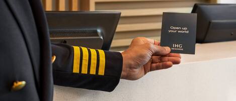 A person in uniform holding a card with "IHG Rewards" text.