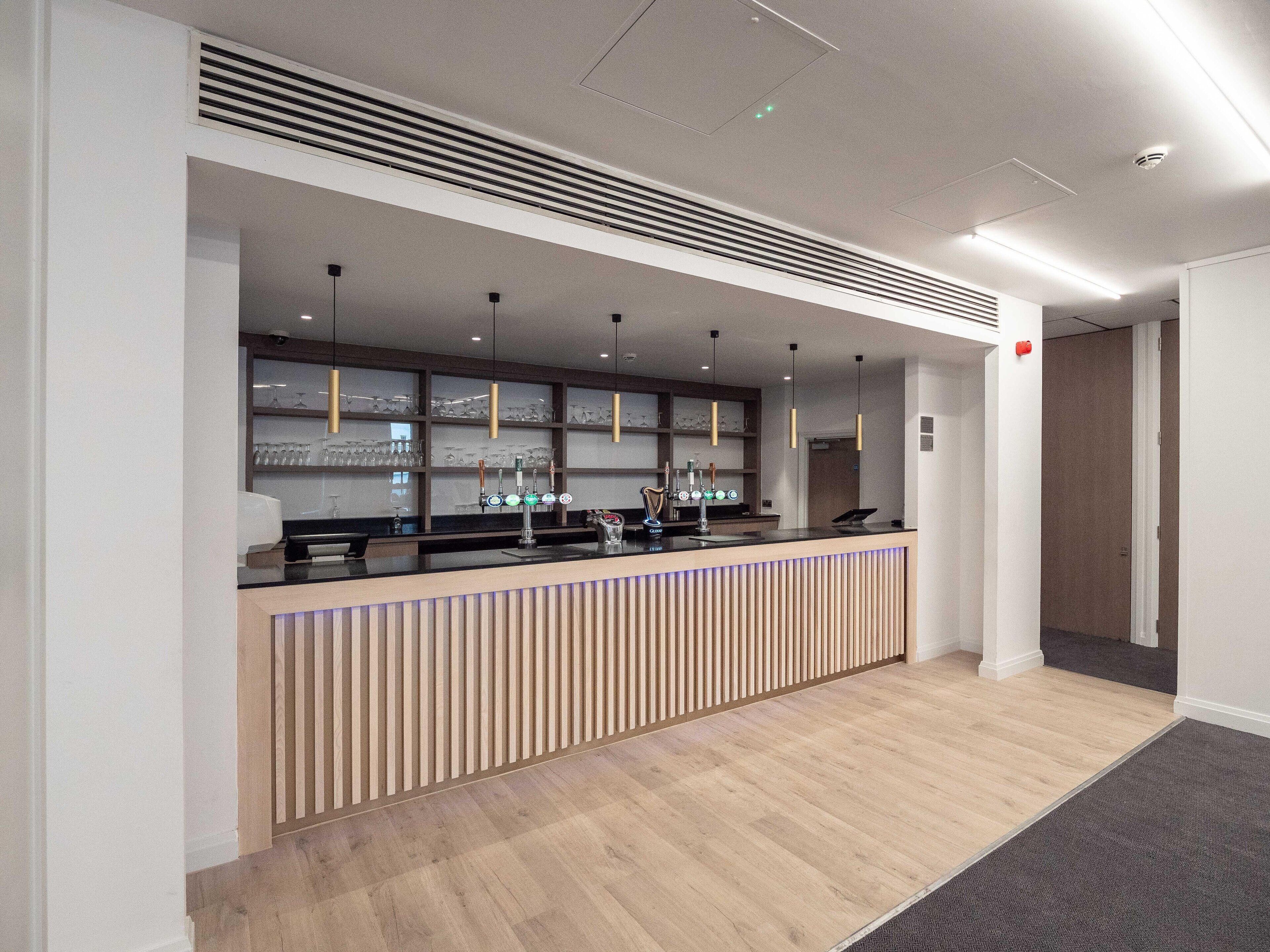 A modern reception area with a wooden counter, glass display shelves, and pendant lighting.