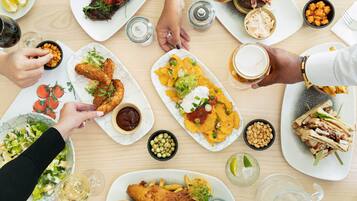 Una mesa de comedor con diversos platos, incluyendo pescado, patatas fritas y sándwiches.