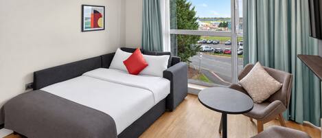Una habitación de hotel con una cama, un sofá, una mesita y una silla.