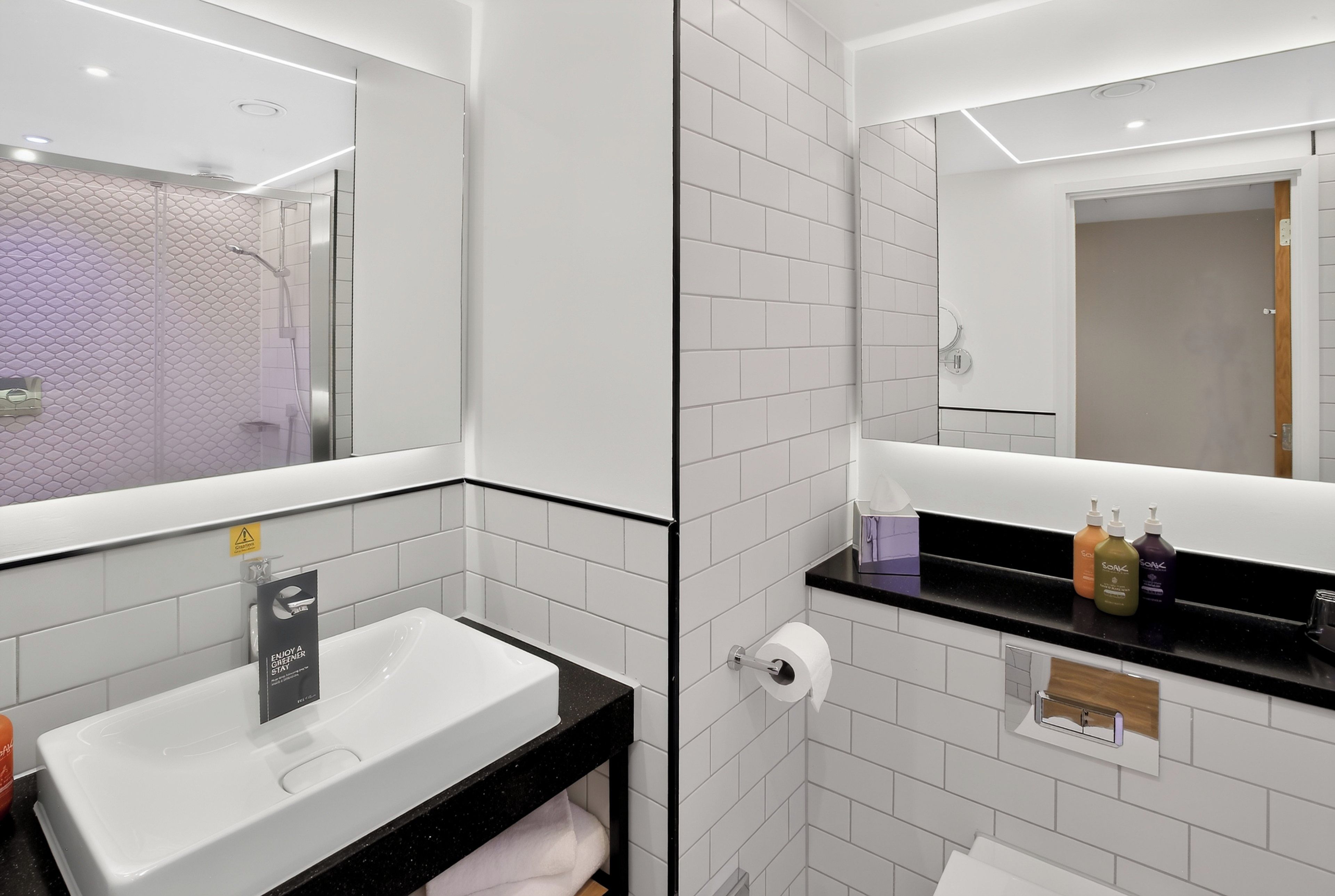 A modern bathroom with a white sink, black countertop, and a mirror.