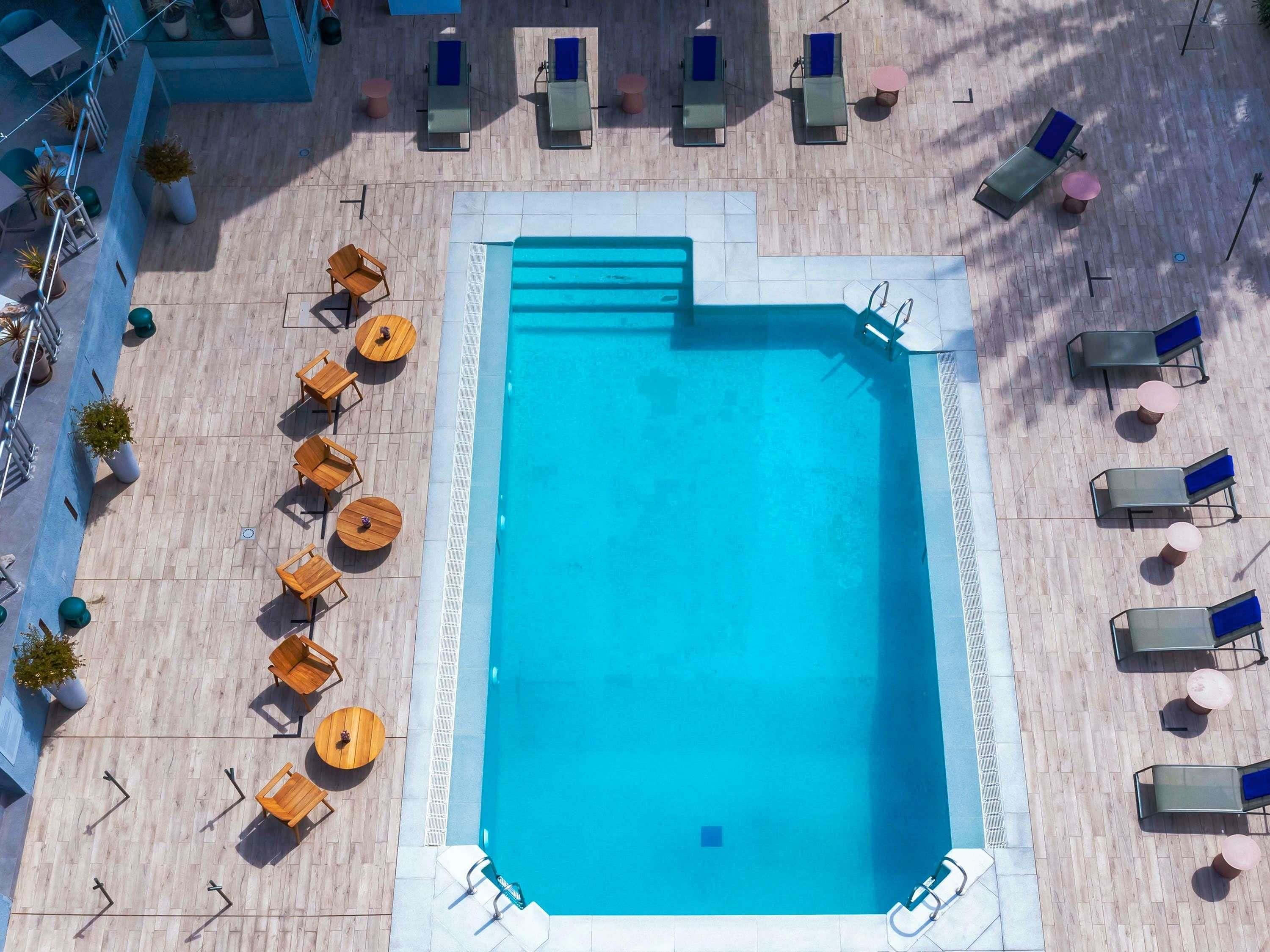 Uma área de piscina no terraço, com espreguiçadeiras e mesas dispostas ao redor.