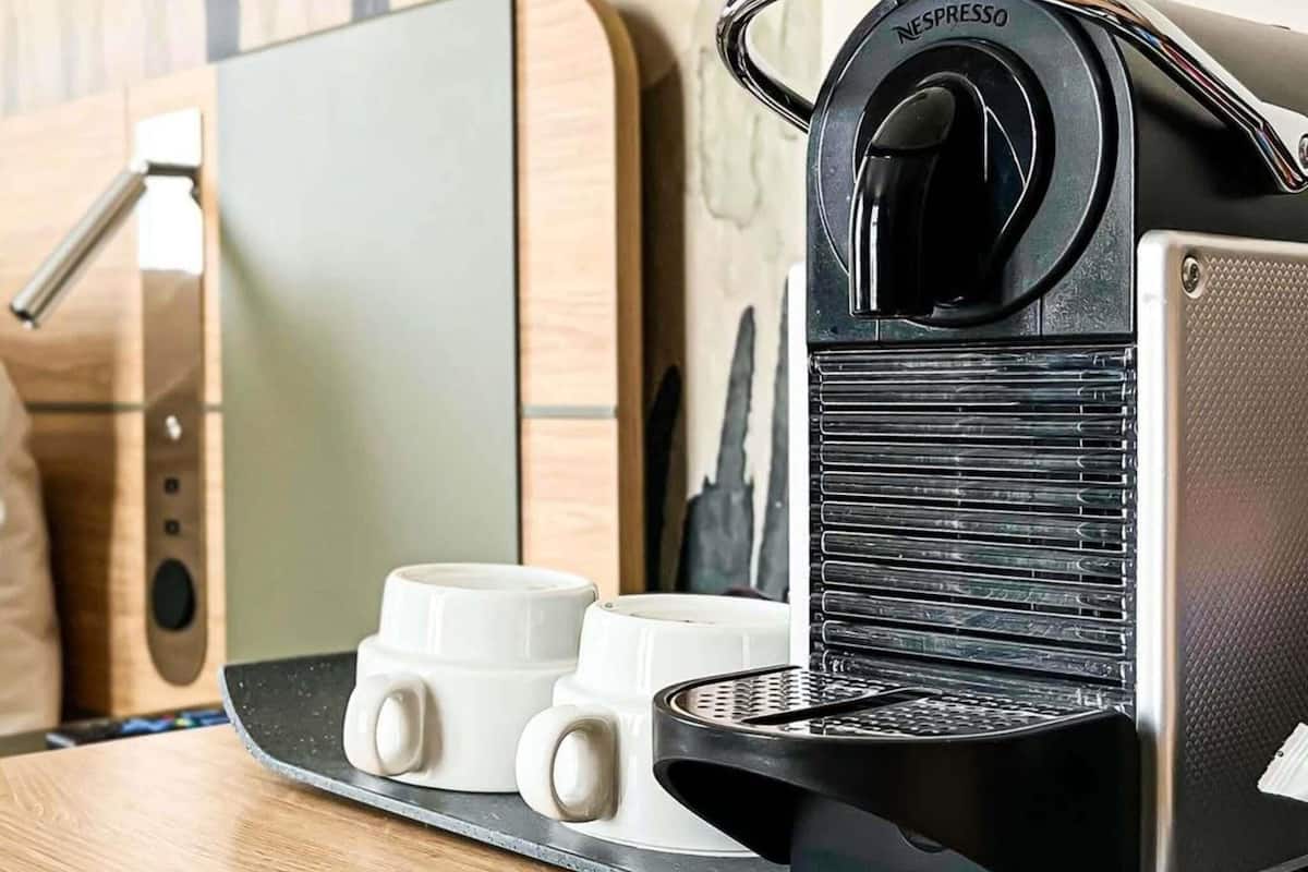 A Nespresso coffee machine with two white coffee cups on a countertop.