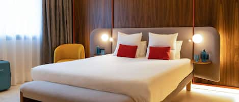 A modern hotel room with a large bed, a bench, wooden paneling, and bedside lamps.