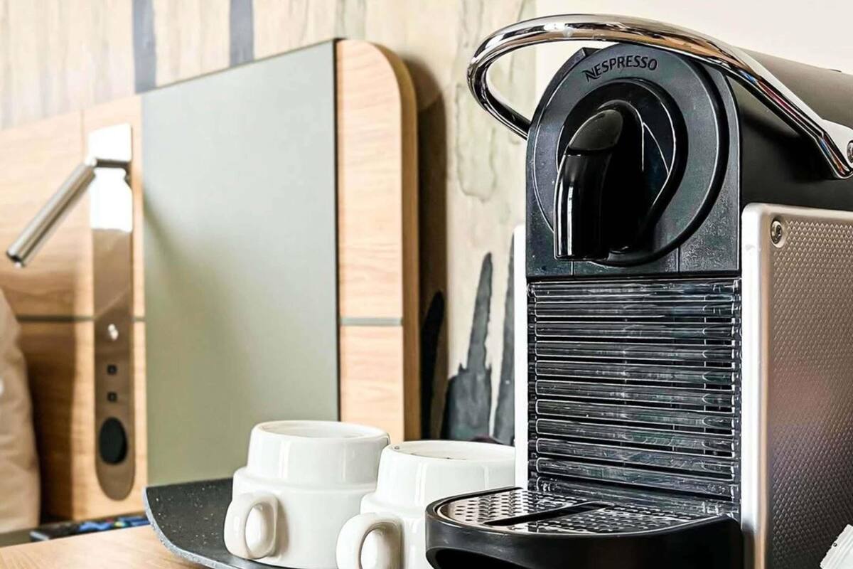 A Nespresso coffee machine with two white coffee cups on a countertop.