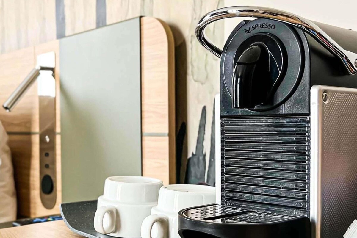A Nespresso coffee machine with two white coffee cups on a countertop.