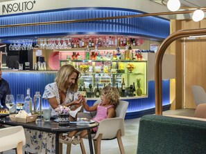 Zona de bar con mostrador azul, varias botellas y un cartel que dice 'INSOLITO'.