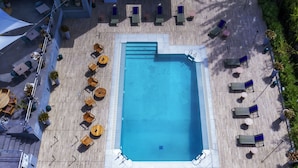 Vista aérea de una zona de piscina en la azotea, con múltiples sillas de descanso y mesas dispuestas alrededor.