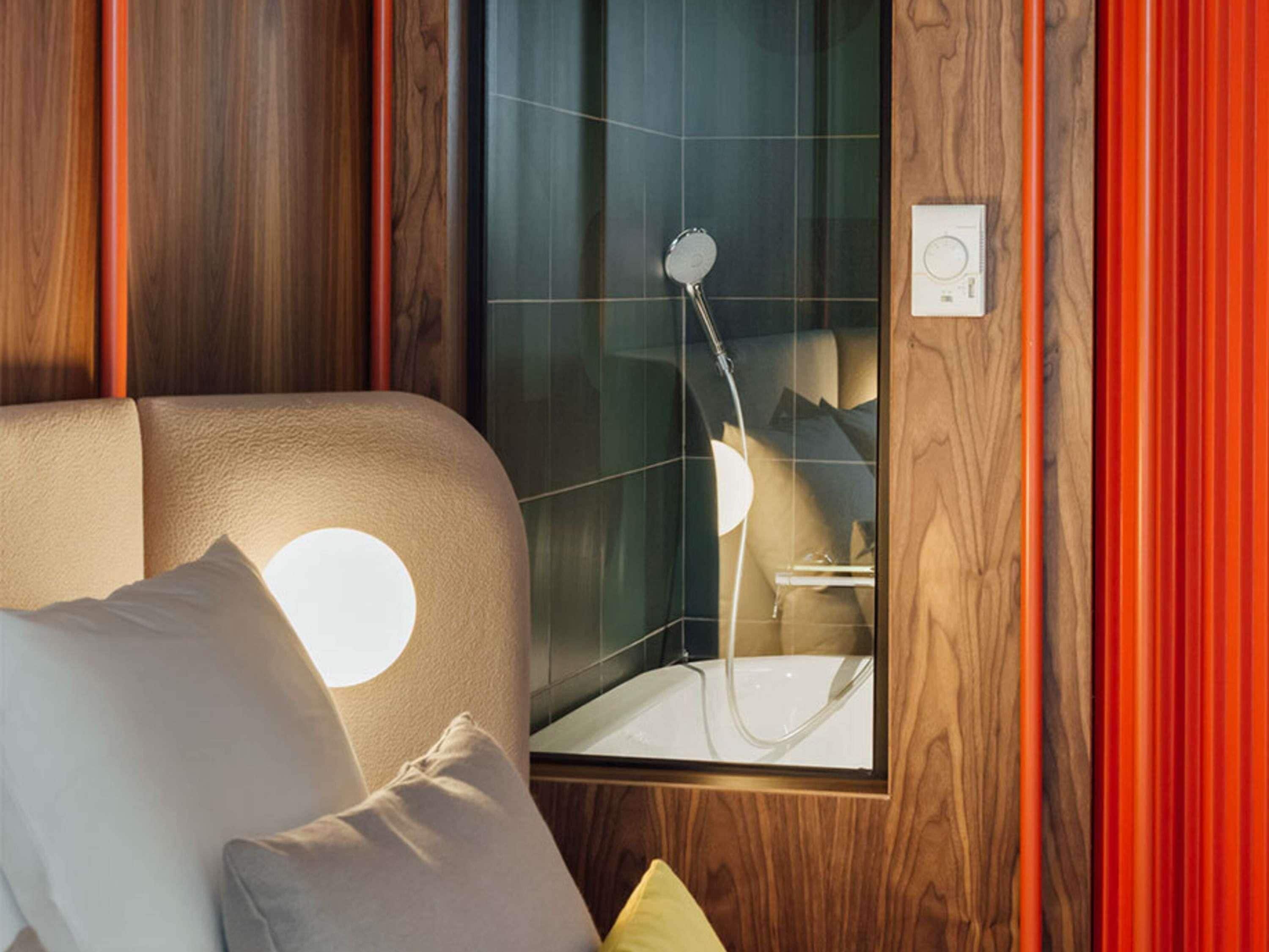 Un bagno moderno con doccia vetrata, rivestimento in legno e pannello di controllo a vista.