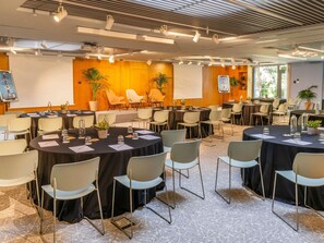 Un salón de conferencias con varias mesas y sillas, equipado con proyectores e iluminación.