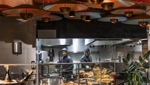 Una cocina moderna con electrodomésticos de acero inoxidable, un mostrador tipo buffet con diversos platos, e iluminación colgante.