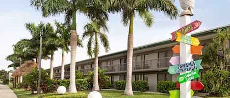 A hotel entrance with a colorful signpost featuring destinations like Panama City Beach and Fort Myers.