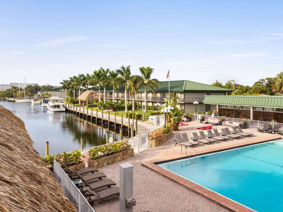 A hotel with a swimming pool, lounge chairs, and a view of the marina.