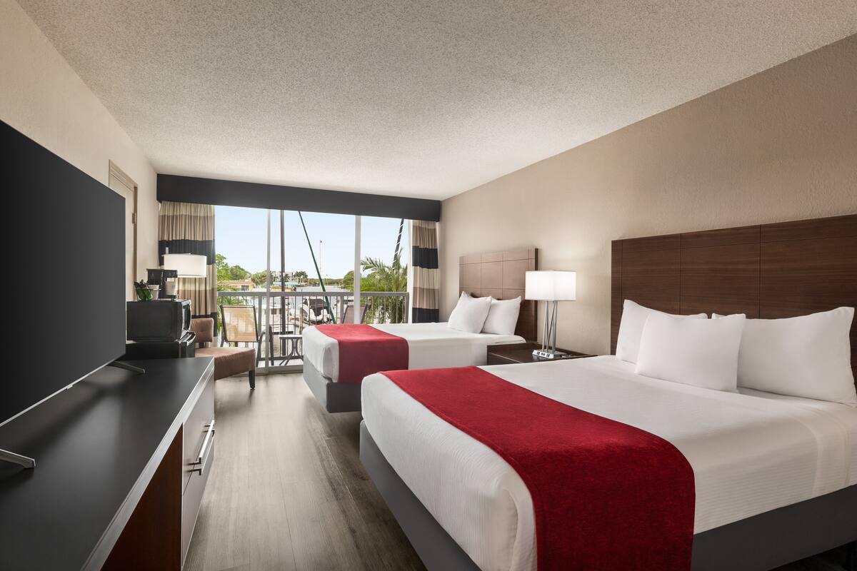 Une chambre d’hôtel avec deux lits, un bureau et un balcon offrant une vue.