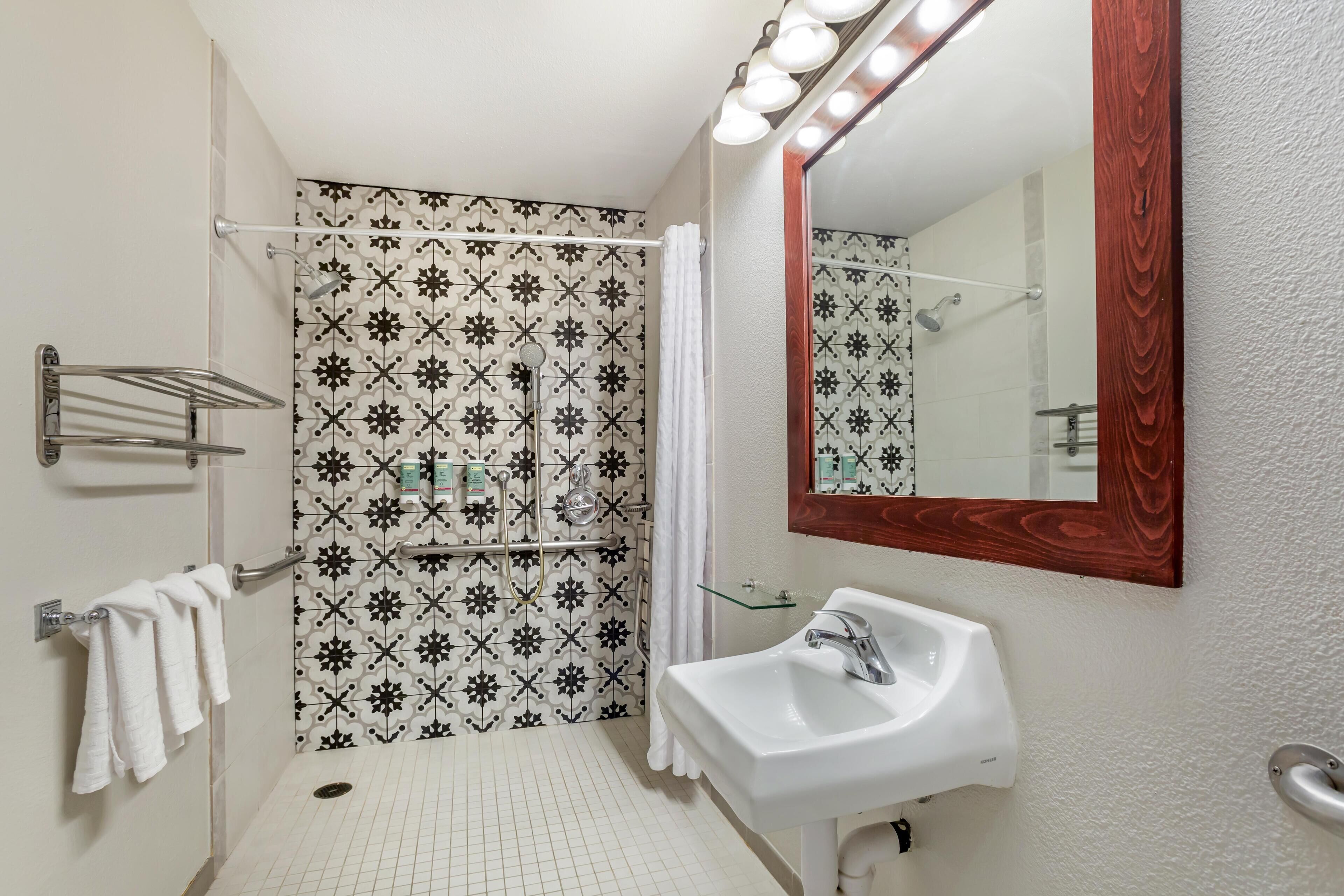 Une salle de bain avec une douche, un lavabo et un miroir.
