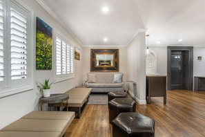 Relax in a spacious living area with a comfortable sofa, ottomans, and a potted plant.