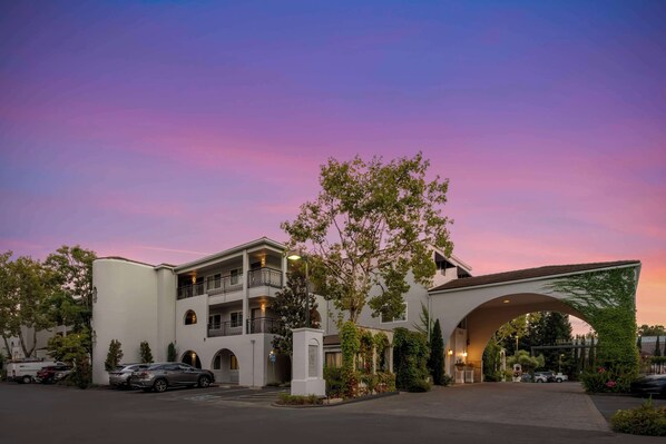 Experience the grandeur of this hotel, featuring a striking arched entrance surrounded by lush greenery and multiple levels with balconies.