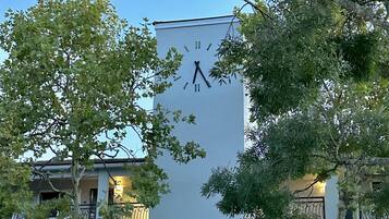 Un bâtiment orné d’une horloge sur sa façade, entouré d’arbres et de balcons.