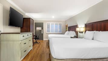 A hotel room with two beds, a TV, a desk, and a chair.