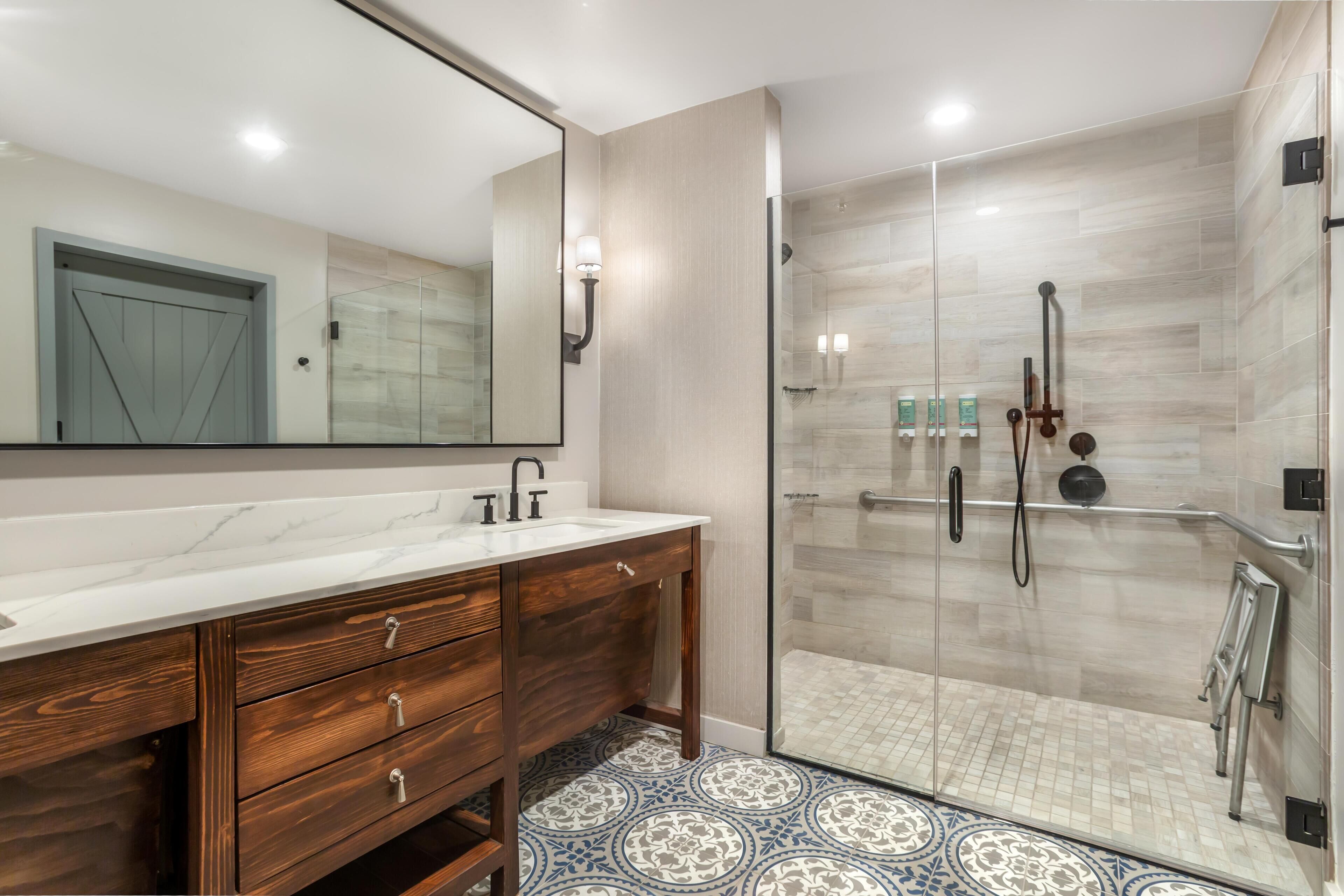 A modern bathroom with a marble sink, wooden vanity, and a glass-enclosed shower area.